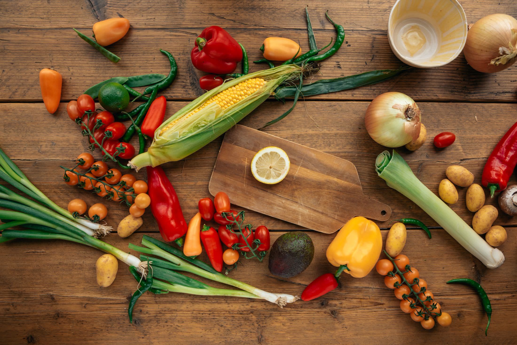 Fresh Latin American ingredients on a wooden table: corn, peppers, avocado and chilies